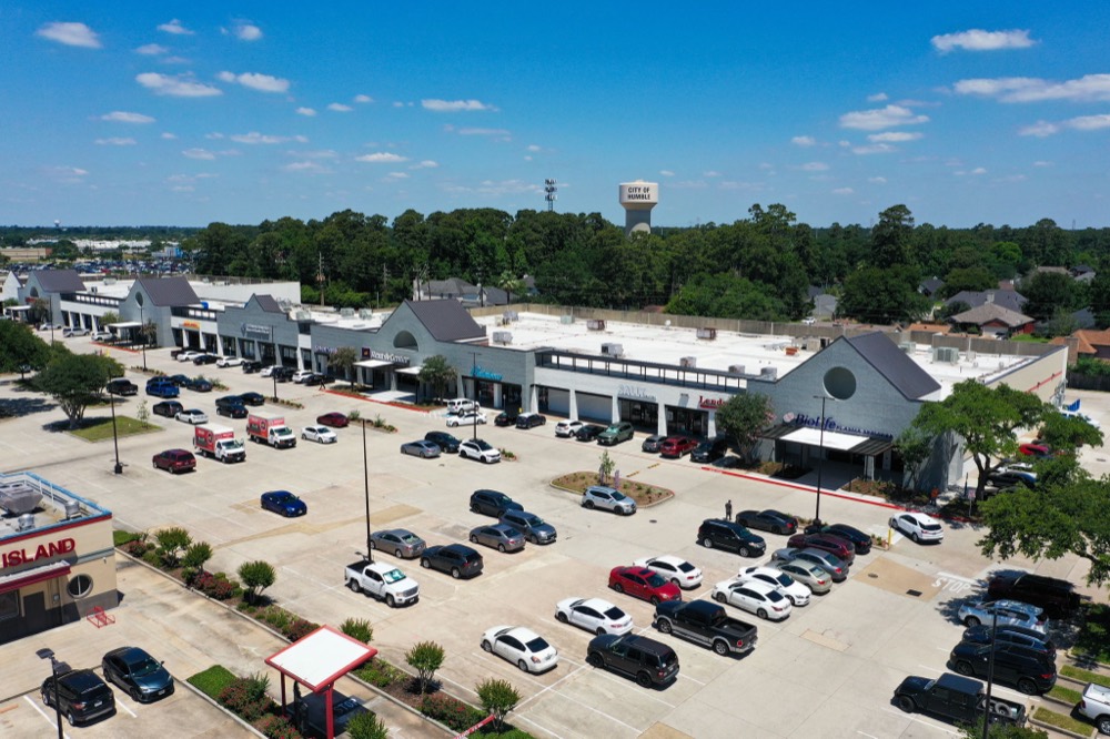 Aerial of Deerbrook Shopping Center with the City of Humble water tower beyond