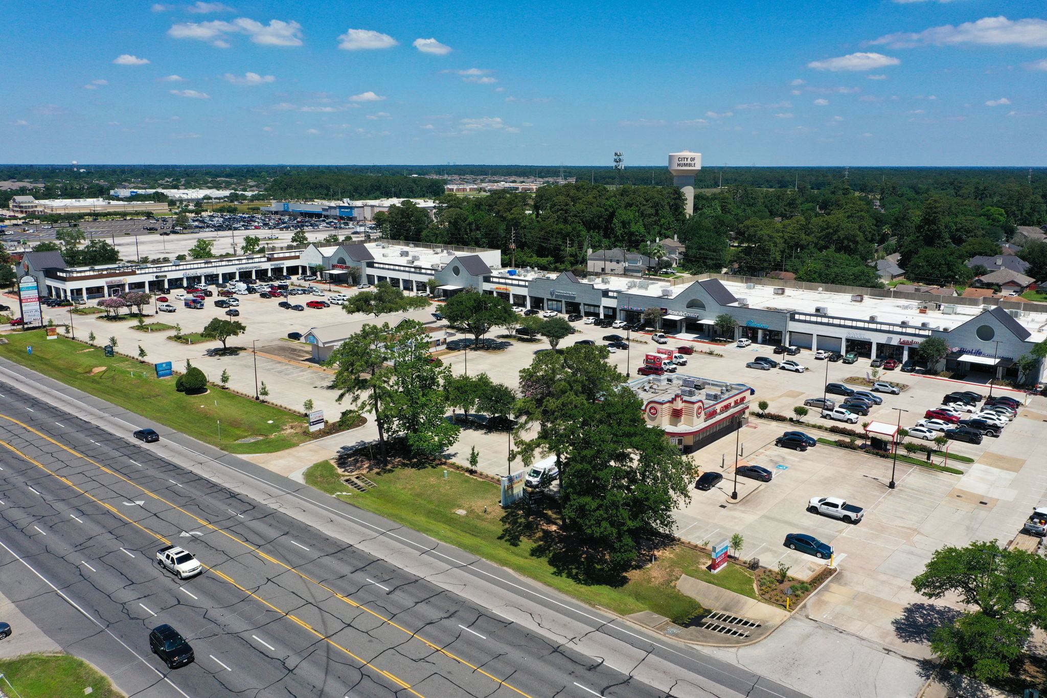 The renovated Deerbrook Shopping Center from across FM 1960, with the James Coney Island pad and the City of Humble water tower
